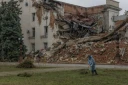 Un employé municipal ramasse de l'herbe coupée près d'un bâtiment administratif en partie détruit par une frappe russe, le 30 octobre 2026 à Kherson, dans le sud de l'Ukraine 