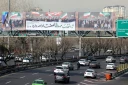 La passerelle piétonne d'une autoroute sur laquelle est déployée une immense banderole montrant des personnes agitant le drapeau iranien, à Téhéran, le 18 février 2026