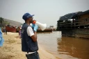Mégaphone à la main, Yves Matwa, agent de la riposte à Ebola, passe les consignes aux passagers d’une baleinière, au port de Bende-Bende, commune de Maluku, à 70 km au nord-est de Kinshasa, le 20 août 2026