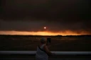 Une femme observe la fumée depuis la plage à Andernos-les-Bains lors d'un incendie dans la forêt de Lège-Cap-Ferret, dans le sud-ouest de la France, le 23 juillet 2026, alors qu'une partie de la zone voisine a été évacuée
