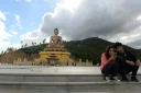 Un couple assis regarde l'écran d'un téléphone portable à côté d'une statue de Bouddha à Thimphou, la capitale du Bouthan, le  25 août 2018