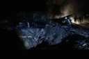 Un pompier ukrainien examine un cratère après une frappe de missile russe qui a touché des habitations à Kiev dans la soirée du 21 octobre 2026