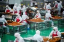 Des ouvriers préparent des lamelles de farine pour les aromatiser avant leur conditionnement à l'usine Mala Wangzi, du comté de Pingjiang, dans la province du Hunan, le 17 juin 2026 dans le centre de la Chine
