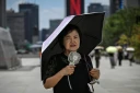 Une femme sous un parapluie avec un ventilateur portatif, le 12 juillet 2026 à Séoul 
