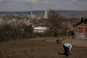 Un homme travaille dans son jardin qui surplombe une centrale thermique au charbon, près de la ville d'Obilic, au Kosovo, le 10 avril 2026