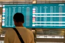 Un passager bloqué à l'aéroport international Soekarno-Hatta en raison de l'éruption du volcan Anak Krakatau, regarde un écran d'information sur les vols, le 7 septembre 2026 à Tangerang, en Indonésie