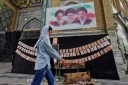 Une passante marche à côté des portraits des trois guides suprêmes de l'histoire de la République islamique d'Iran, l'ayatollah Rouhollah Khomeini, l'ayatollah Ali Khamenei et Mojtaba Khamenei (de gauche à droite), et de photos d'enfants tués lors du bombardement de l'école de Minab en février, le 25 avril 2026 à Téhéran