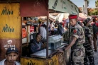 Au lendemain de la prise de pouvoir, un soldat de l'unité Capsat discute avec une vendeuse près de sa base militaire à Antananarivo, le 15 octobre 2025