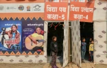Des enfants se tiennent à l'entrée d'une école de fortune, construite pour les enfants des personnels de santé, avant le festival Maha Kumbh Mela à Prayagraj en Inde, le 11 janvier 2025