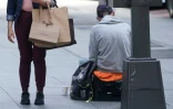 Une passante sur la 5th Avenue à New York et une personne faisant l'aumône. Malgré la forte hausse des bas salaires aux Etats-Unis, les inégalités s'aggravent.