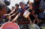 Des jeunes Palestiniens tentent d'obtenir du riz distribué par une cuisine caritative dans l'ouest de Gaza, le 28 août 2025