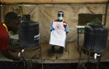 Un membre du personnel sanitaire veille à ce que les gens se lavent les mains pour lutter contre l'épidémie d'Ebola à la frontière entre la RDC et l'Ouganda, le 13 juin 2019.