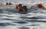 Des migrants nagent alors qu'ils tentent de monter à bord d'un bateau de passeurs pour traverser la Manche au large de la plage de Gravelines, le 16 juin 2025 dans le Nord