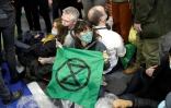 Des militants du mouvement écologiste Extinction Rebellion manifestent en s'enchaînant au pied du stand de la FNSEA lors du Salon de l'agriculture, le 27 février 2022 à Paris