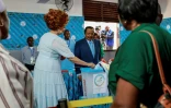 Le président camerounais sortant Paul Biya (G) regarde son épouse Chantal glisser son bulletin dans l'urne dans un bureau de vote à Yaoundé, le 12 octobre 2025