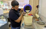 Samir Makari verse le tahini pour préparer la mfatka dans sa boutique à Beyrouth, le 29 août 2024 au Liban