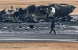 Une personne examine l'épave d'un avion des garde-côtes japonais à l'aéroport de Tokyo-Haneda le 3 janvier 2024 après la collision de l'appareil la veille avec un avion de ligne de la Japan Airlines