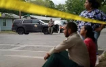 Des gens assis sur le trottoir à l'extérieur de l'école primaire Robb, à Uvalde au Texas, après la fusillade, le 24 mai 2022 ( AFP / allison dinner )