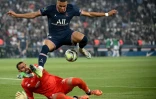 L'attaquant du Paris Saint-Germain Kylian Mbappé saute au-dessus du gardien de Metz Marc-Aurèle Caillard durant la rencontre entre les deux clubs le 21 mai 2022 au Parc des Princes à Paris