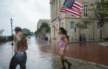 Un homme agite le drapeau américain face au vent et à la pluie quelques heures avant l'arrivée de l'ouragan Florence à Wilmington, en Caroline du Nord, le 13 septembre 2018
