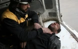 Un secouriste syrien assiste un homme blessé par un bombardement du régime sur la localité de Hammouriyé dans la Ghouta orientale, le 22 février 2018