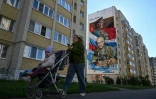 Une mère de famille passe devant une fresque représentant un colonel de l'armée russe et un ancien ministre de la Défense de l'Union soviétique, à Tambov, en Russie, le 9 septembre 2026