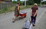 Des habitantes transportent des bouteilles d'eau remplies à un puits, le 30 juin 2022 à Seversk, dans la région de Donetsk, en Ukraine