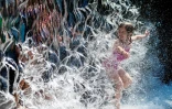 Une fillette se rafraîchit dans une cascade dans un parc de Washington, le 28 juin 2021