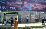 Des habitants attendent un bus devant une affiche géante du chef d'état-major de l'armée pakistanaise Asim Mounir, dans une rue àRawalpindi, le 14 mai 2025 au Pakistan
