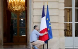 Un homme arrange les drapeaux à l'entrée de l'Hôtel de Matignon, le 30 juin 2024