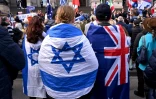 Des gens enveloppés du  drapeau australien et israélien lors d'un rassemblement à Melbourne après une tentative d'incendie visant une synagogue dans la ville, le 6 juillet 2025 