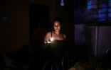 Une femme s'éclaire à la bougie pendant une coupure d'électricité, à la Havane, le 25 mai 2022