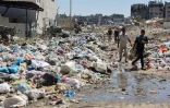 Des Palestiniens passent devant des monticules d'ordures et des égouts dans le quartier de Cheikh Radwane, au nord de la ville de Gaza, le 3 juillet 2024