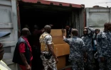 Des membres de l'unité de lutte contre la criminalité organisée transnationale ouvrentl’un des conteneurs saisis contenant des comprimés et gélules de tapentadol en provenance d’Inde, au terminal de Freetown, le 27 mars 2026 en Sierra Leone