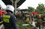 Des pompiers, des policiers et des secouristes autour de la carcasse d'un bus détruit par un incendie lors d'un voyage scolaire, près de Bangkok, en Thaïlande, le 1er octobre 2024
