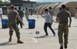 Des enfants afghans jouent au foot avec des soldats américains, sur la base aérienne américaine de Ramstein, en Allemagne, le 26 août 2021. Photo distribué par le service de relations publique de l'armée américaine
