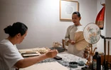 Yang Yun (d), fondatrice de l'espace de cohabitation pour femmes "Her Space", regarde une invitée faire de la calligraphie à Hangzhou, le 14 juillet 2025 dans la province du Zhejiang, dans l'est de la Chine
