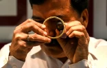 Un gérant de bijouterie examine à la loupe un bracelet en or, le 11 octobre 2021 à Bombay, en Inde