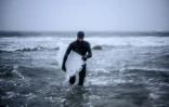Le Suédois Oskar Nordin sort de l'eau après une tentative de surf à Straumnes, au nord de la Norvège, le 19 février 2019