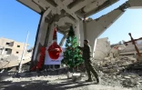 Un membre des Forces démocratiques syriennes devant un sapin de Noël dans ce qui reste de l'église des Martyrs à Raqa le 26 décembre 2017