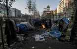 Des migrants notamment d'Afghanistan se réchauffent autour d'un feu de camp à Paris le long du Canal St Martin, le 23 février 2018
