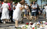 Une femme habillée de blanc se recueille, le 7 août 2016, devant un parterre de fleurs en hommage aux victimes de l'attaque meurtrière du 14 juillet