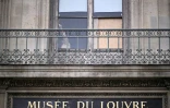 Une personne derrière la fenêtre par laquelle sont entrés les voleurs au musée du Louvre la veille, à Paris, le 20 octobre 2025