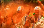 Des gens se protègent du Covid-19 avec des combinaisons pendant les célébrations de Holi, la fête des couleurs en Inde, au cours de laquelle il est de tradition de s'asperger de pigments de couleurs, à Kolkata, le 29 mars 2021