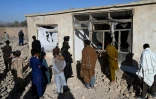 Des habitants devant une maison endommagée par un raid aérien pakistanais, en périphérie de Kaboul, le 13 mars 2026 en Afghanistan