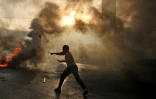 Un manifestant palestinien lance des pierres contre les forces de sécurité israéliennes en Cisjordanie occupée, le 29 mai 2022, jour de la "marche des drapeaux" à Jérusalem