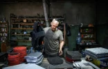 Andriï Paliy prépare un gilet pare-balles avec les plaques de métal qu'il a fabriquées dans un atelier de Zaporijjia, le 1er mai 2022 en Ukraine