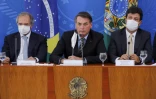 Le président brésilien Jair Bolsonaro (c) entouré de son ministre de l'Economie Paulo Guedes (g) et de la Santé Henrique Mandetta (d), lors d'une conférence de presse à Brasilia, le 18 mars 2020