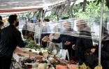 Un film plastique entre des clients et des vendeurs de fruits et légumes sur un marché à Paris en mai 2020