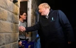 Boris Johnson apporte une bouteille de lait à Debbie Monaghan à Guiseley, le 11 décembre 2019 dans le cadre de sa campagne électorale